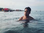 一名年轻人在帕苏昆海滩宁静的海水中游泳，尽显休闲本色