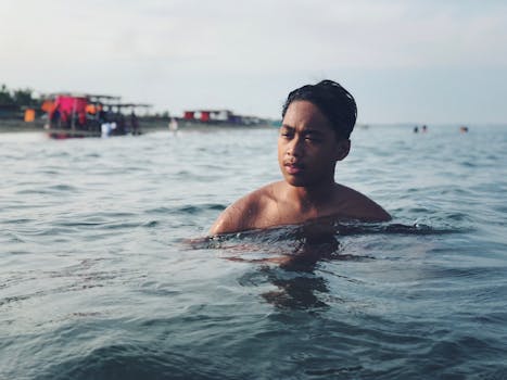 一名年轻人在帕苏昆海滩宁静的海水中游泳，尽显休闲本色