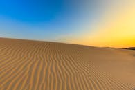 金色的沙丘横贯沙漠，映衬在充满活力的日出天空下