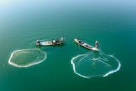 无人机拍摄了在宁静的绿水上撒网的渔民