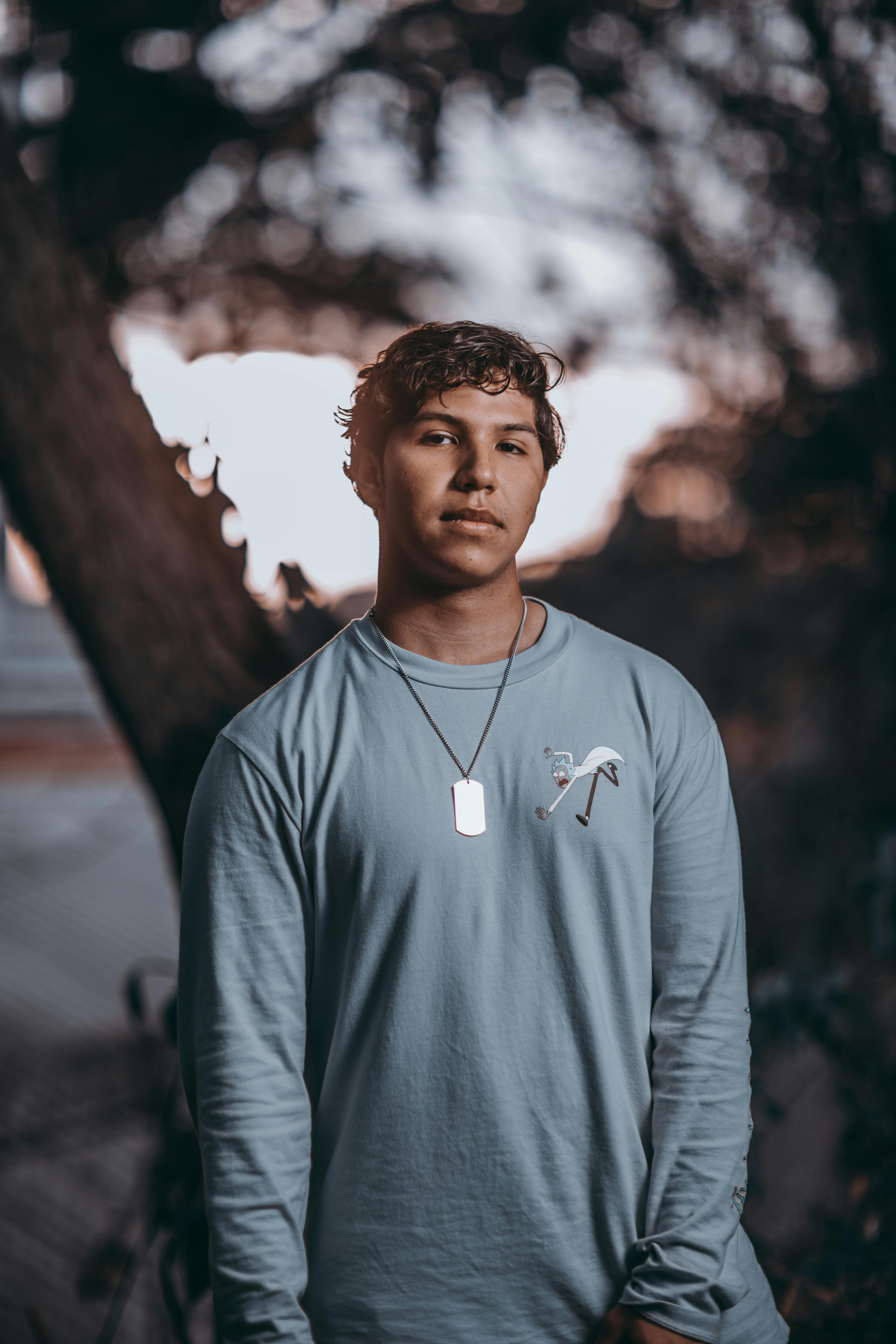 一位英俊的年轻人在户外戴着吊坠和时尚毛衣摆姿势