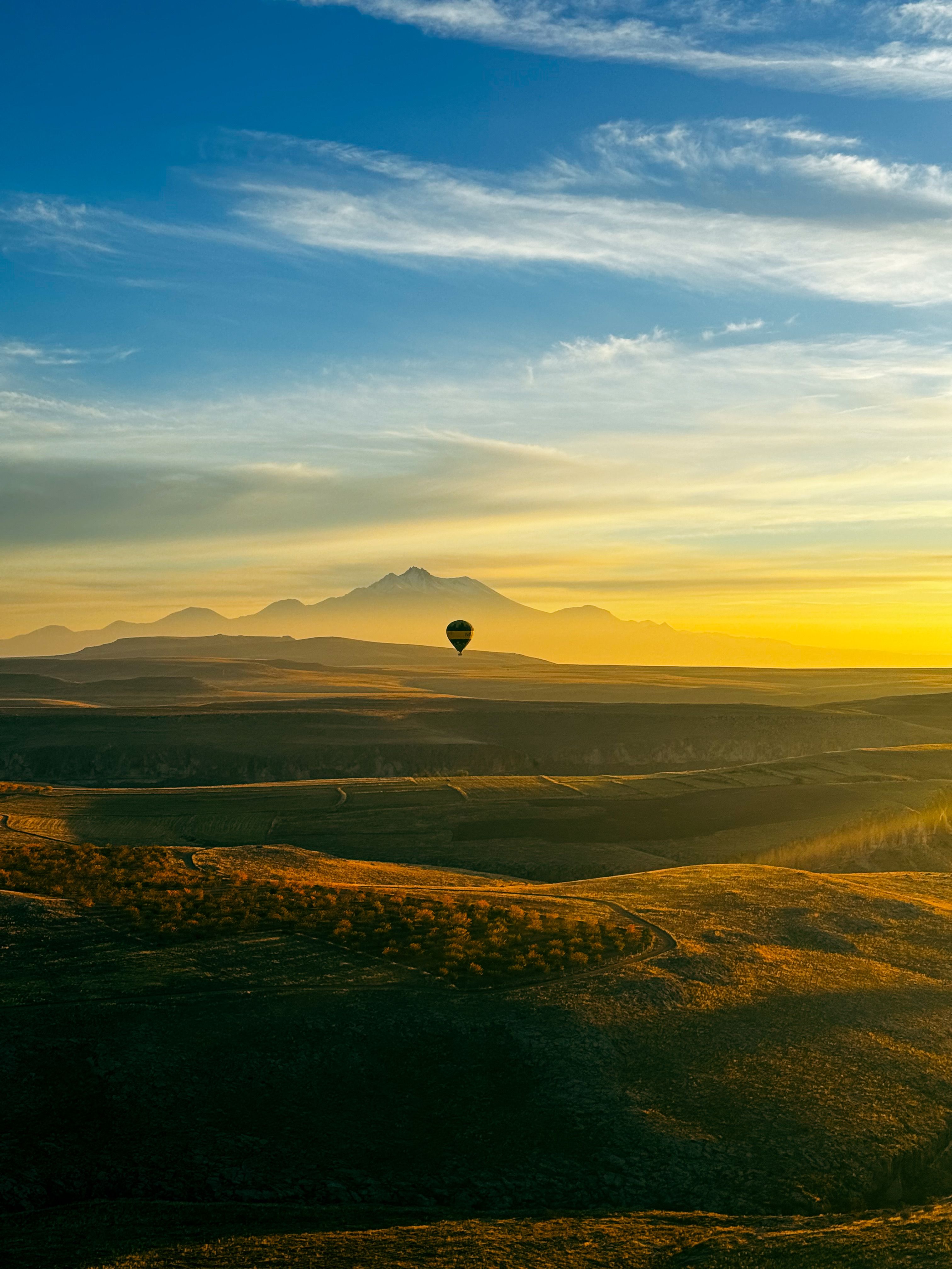 Hot Air Balloon Flying over Scenic Landscape at Dusk · Free Stock Photo