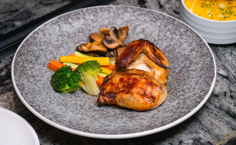 Roast chicken with charred vegetables on a speckled plate — photo by Change C.C on Pexels