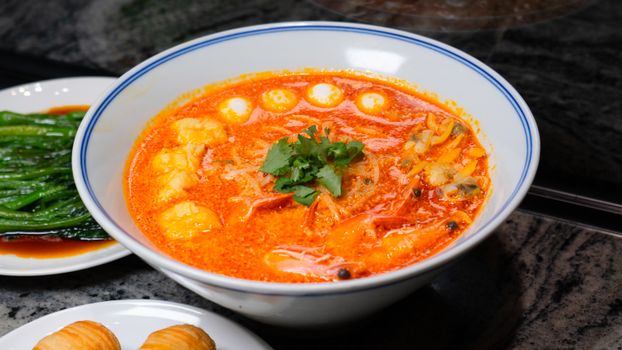 Delicious Thai Tom Yum soup with seafood and vegetables, garnished with cilantro in a ceramic bowl.
