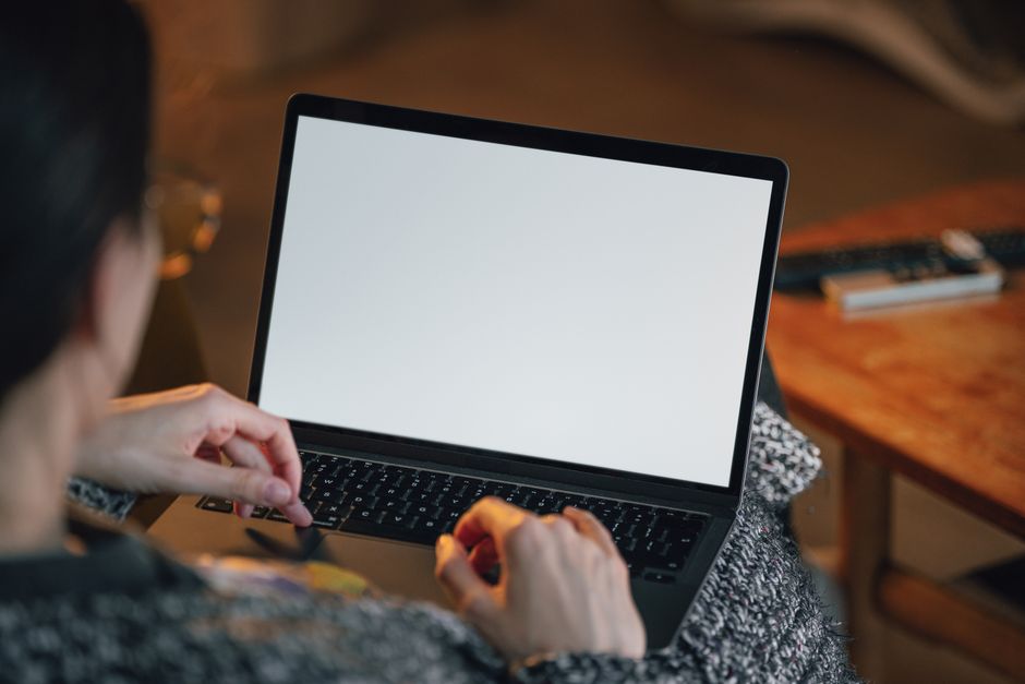 CyberGhost vs Private Internet Access: Torrenting Safety and Speed Myths Debunked Person working remotely with a laptop on lap, blank screen visible.