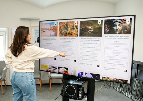 Person checking a social wall with live polls on a TV display in a working space