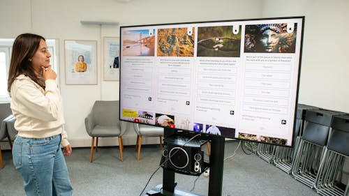 Person checking a social wall with live polls on a TV display in a working space