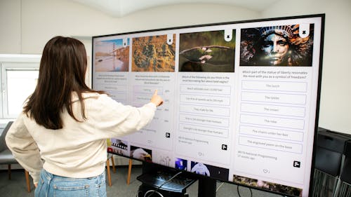 Person checking a social wall with live polls on a TV display in a working space