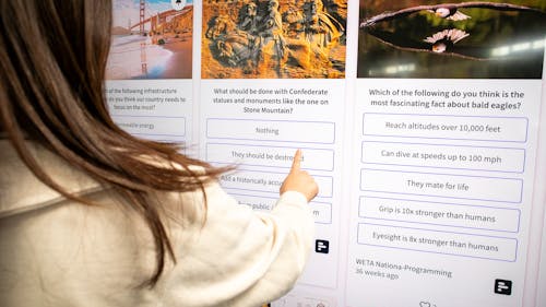 Person checking a social wall with live polls on a TV display in a working space