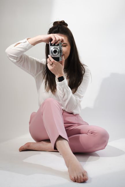 Creative portrait of a young woman holding a retro camera in a studio environment.