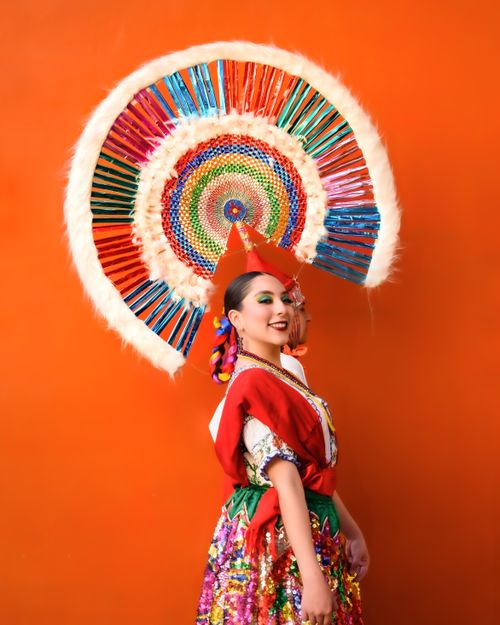 Free Smiling woman in colorful traditional attire against orange background. Stock Photo