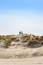 Two people are standing on top of a sand dune