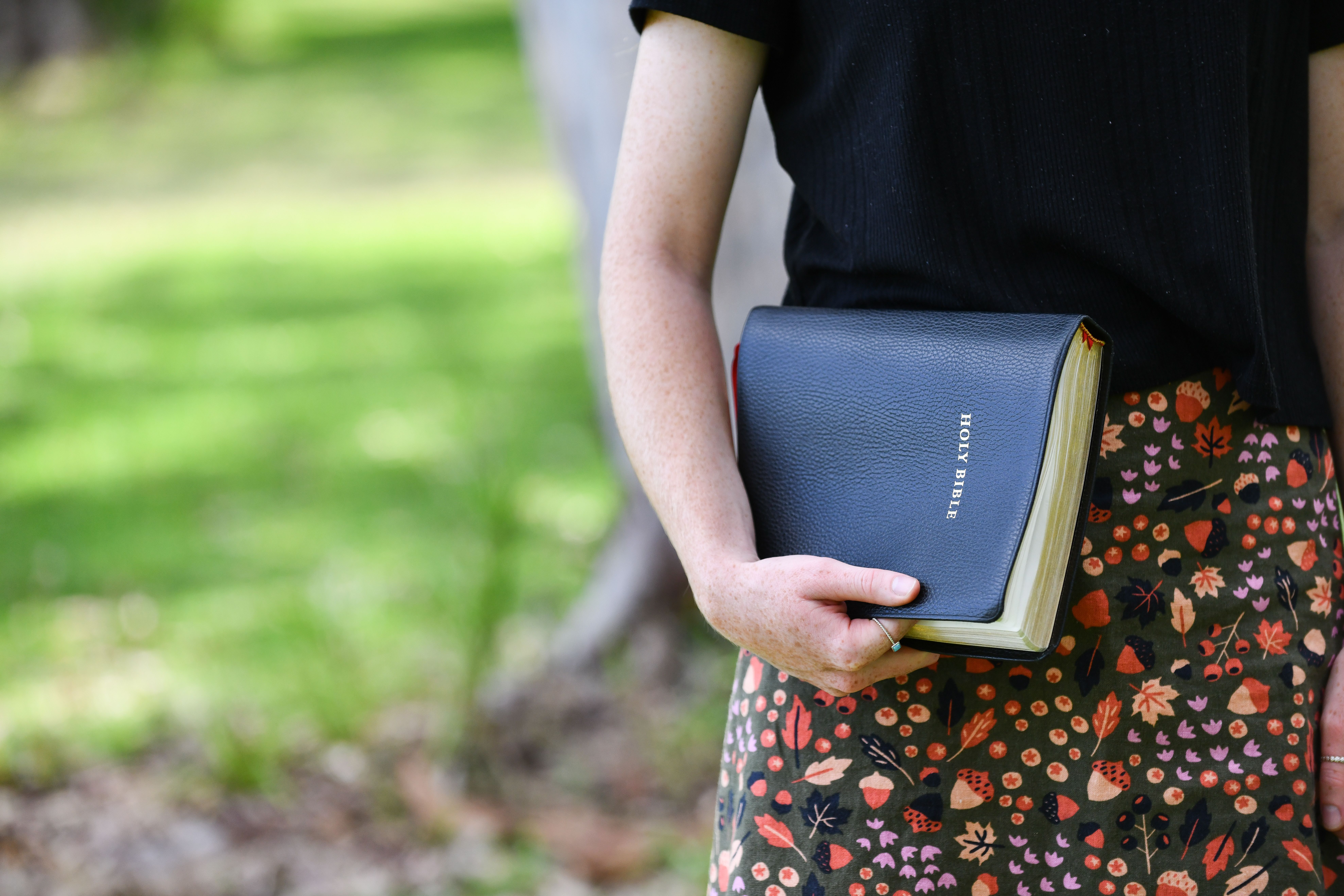 A woman holding a Bible outdoors in natural light