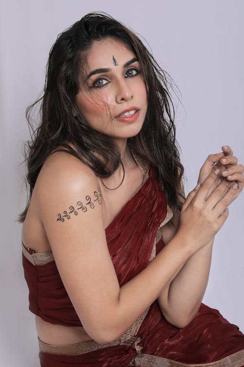 A woman in a red sari with tattoos on her arms