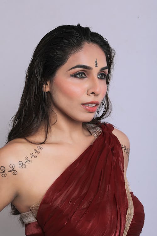 A woman in a red sari with tattoos on her arm