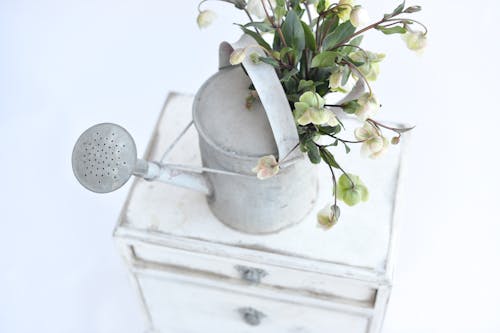 A white metal watering can with flowers on top