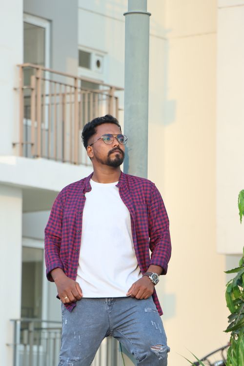 Free Confident man in a casual flannel shirt poses stylishly in a modern urban environment. Stock Photo