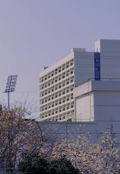 Contemporary urban building with balconies surrounded by trees and a clear blue sky.