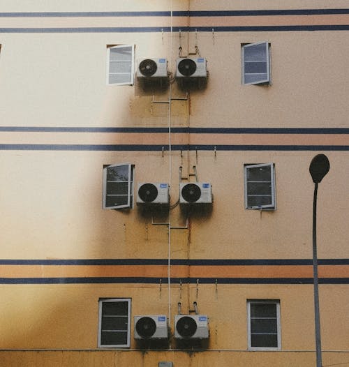 Free A yellow building with several air conditioning units Stock Photo