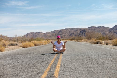 A woman sitting on the side of the road in the desert