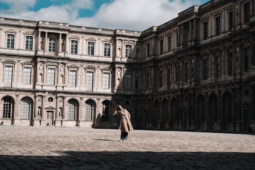 A person walking in front of a large building