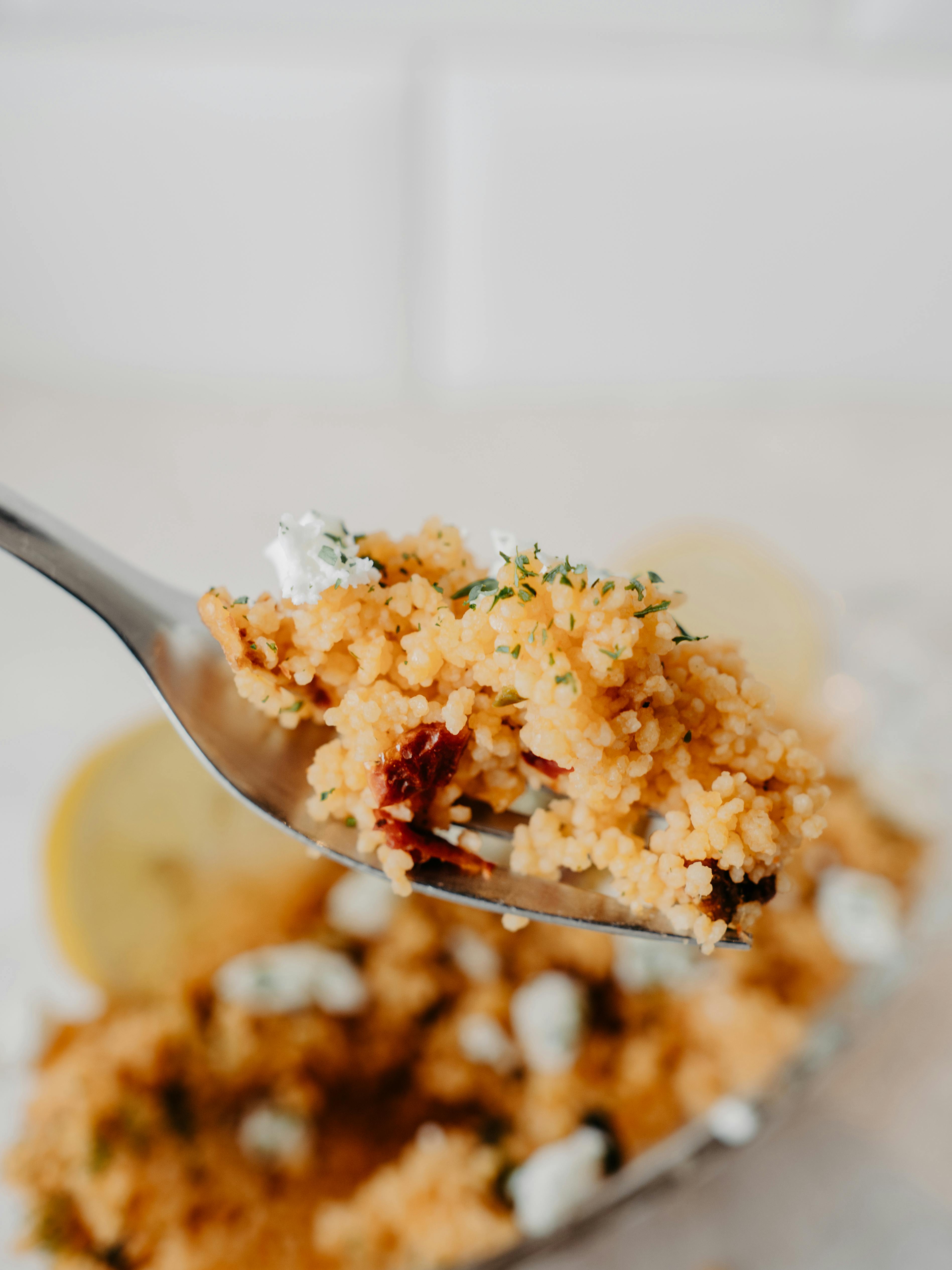 Tantalizing close-up of a forkful of homemade couscous with fresh herbs and lemon.