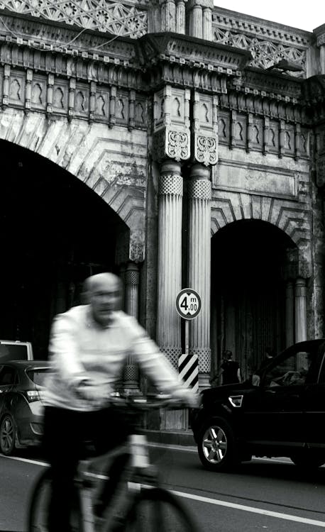 A black and white photo of a man riding a bike