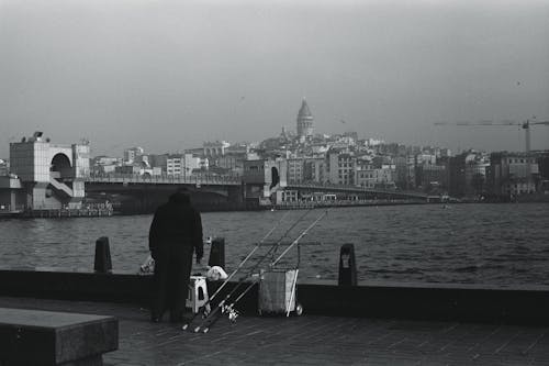 A man is standing on the pier with his fishing rod