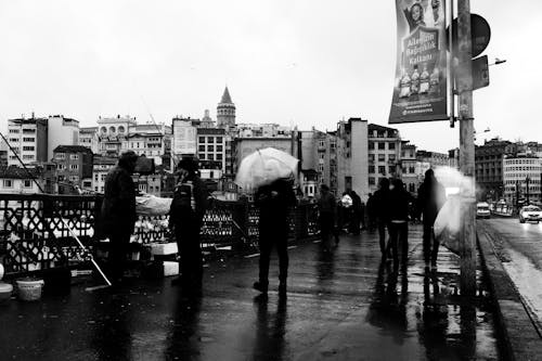 A group of people standing in the rain with umbrellas