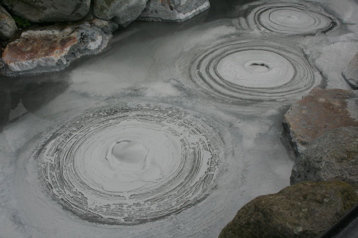 Grey mud bubbling up in rings in a geothermal pool in Beppu