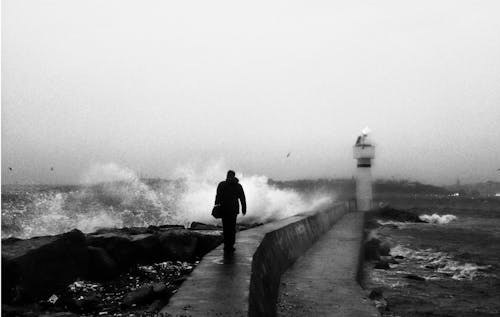 A man walking along the shore with waves crashing in the background