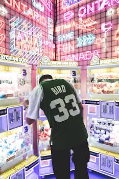 A person interacts with arcade machines under colorful neon lights in Ottawa, creating a lively and fun atmosphere.