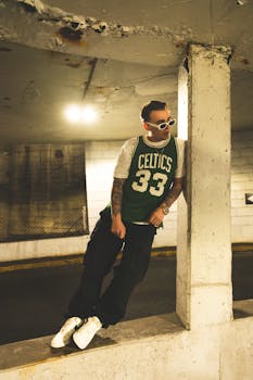 A stylish portrait of a man in a Celtic jersey with tattoos in an urban parking garage, showcasing neon aesthetics.