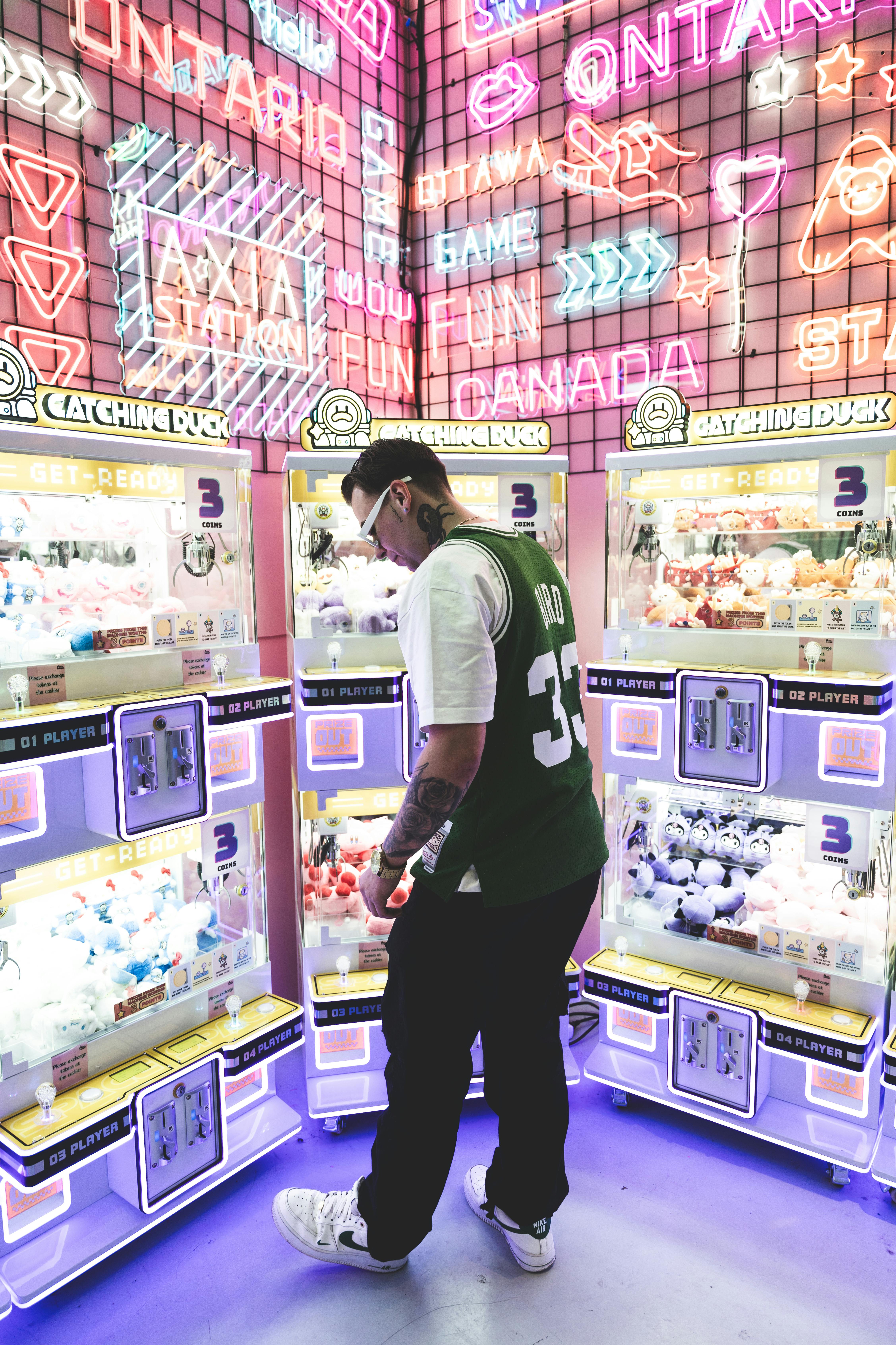 A person explores neon-lit arcade machines in Ottawa mall, Canada.