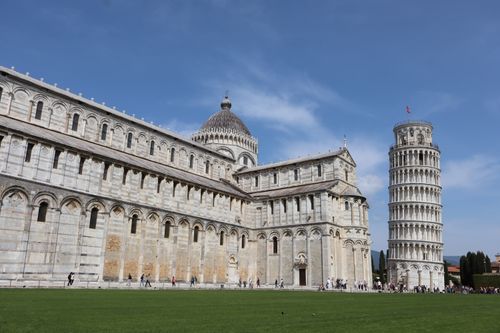 Free Iconic view of the Leaning Tower of Pisa with historical cathedral under a clear blue sky. Stock Photo