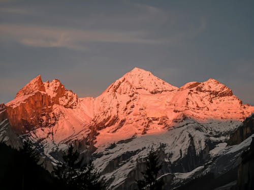 Free A mountain range with snow capped peaks at sunset Stock Photo