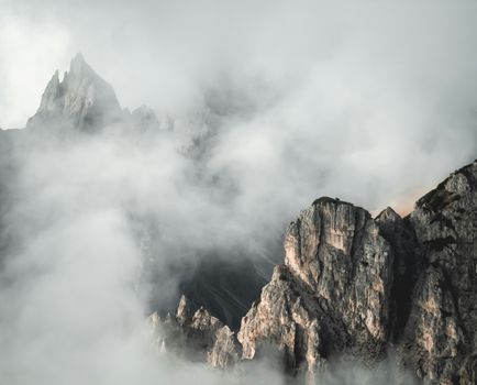 A serene view of rugged mountain peaks enveloped by mist and clouds, highlighting nature's beauty.