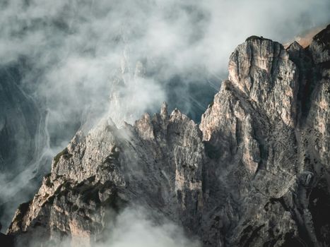 A stunning view of rocky mountain peaks enveloped in dense mist, creating a dramatic natural scene.