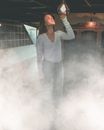 室内烟雾缭绕，灯光迷离，一名穿着休闲装的年轻女子站在其中