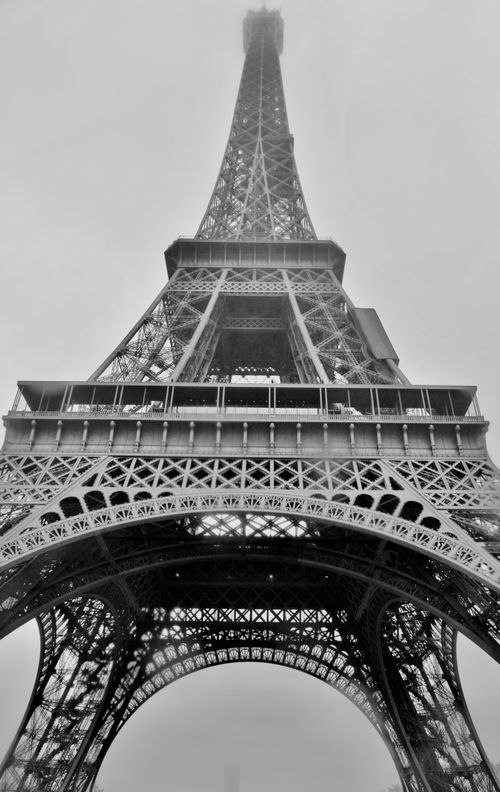 Free Captivating foggy view of the Eiffel Tower in Paris, France, showcasing its iconic iron structure. Stock Photo