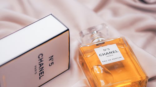 Free Close-up of Chanel No.5 perfume bottle and box on a soft fabric in Paris. Stock Photo