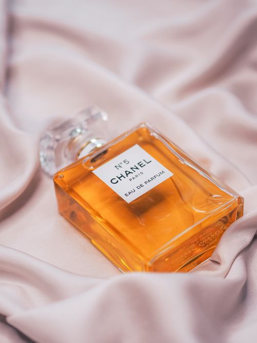 Free Close-up of Chanel No. 5 perfume bottle on soft pink fabric, exuding luxury. Stock Photo