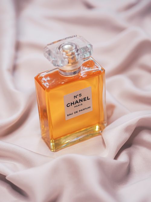 Free Chanel No. 5 perfume bottle elegantly placed on luxurious silk fabric, showcasing exquisite design. Stock Photo
