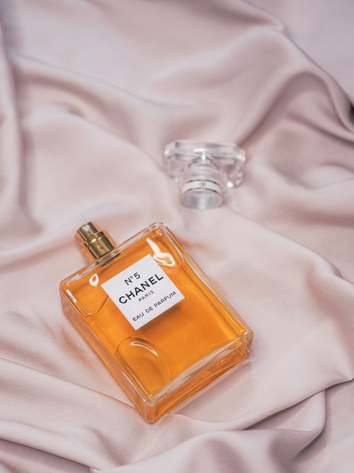 Free Luxurious Chanel No. 5 perfume resting on elegant silk fabric, capturing a sense of timeless glamour. Stock Photo
