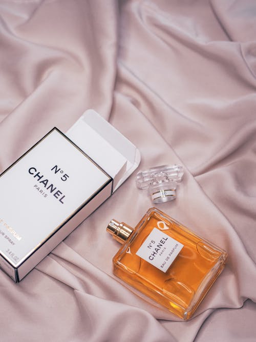 Free Chanel perfume bottle and box on a bed Stock Photo