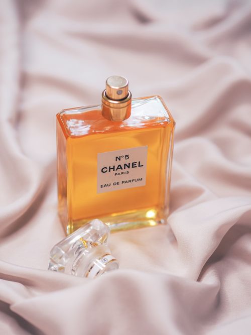 Free Elegant Chanel No. 5 perfume bottle displayed on luxurious silk fabric, capturing sophistication and style. Stock Photo