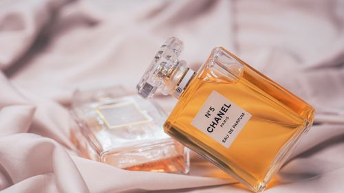 Free Close-up of Chanel No. 5 perfume bottles elegantly placed on soft pink fabric. Stock Photo