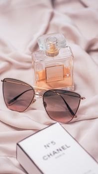 Stylish display of Chanel No.5 perfume and fashionable sunglasses on a soft satin fabric.