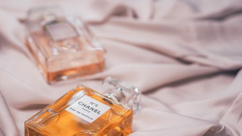 Free Close-up of Chanel No. 5 perfume bottles elegantly displayed on soft silk fabric conveying luxury. Stock Photo