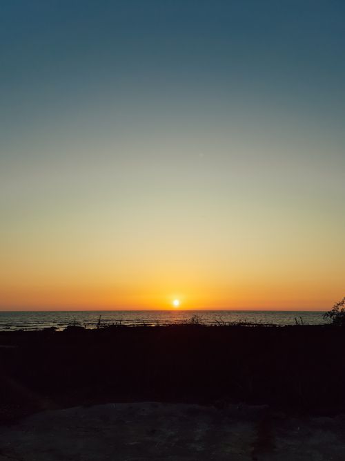 Free Tranquil ocean sunset with vibrant sky and silhouette foreground, capturing nature's beauty. Stock Photo
